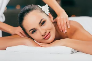 woman relaxing and having massage at spa salon and looking at camera