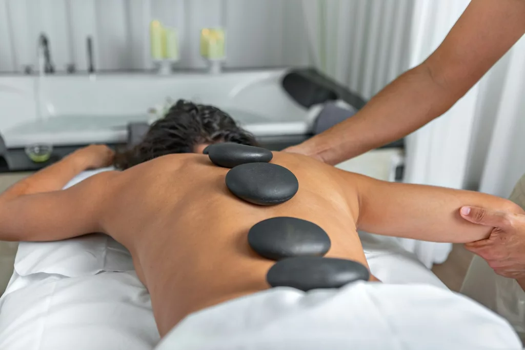 woman having hot stone massage in spa salon while getting an arm and shoulder massage
