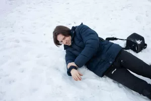 A man falls in the snow. The man slipped and was injured. Falling on ice. Winter. Fracture, bruise