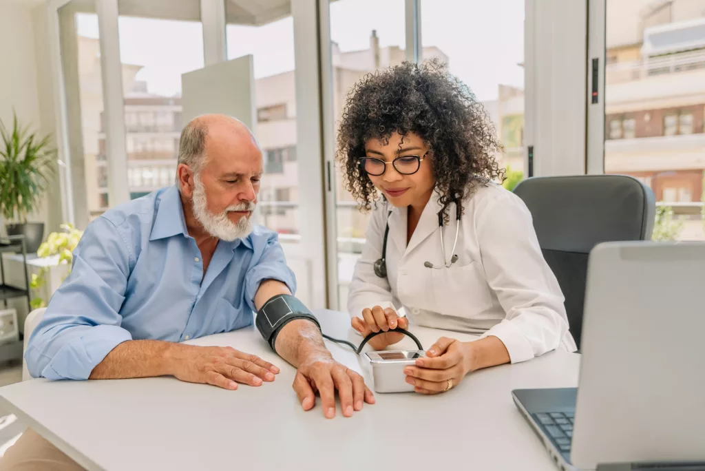 hispanic physician measuring the blood pressure of her elderly patient