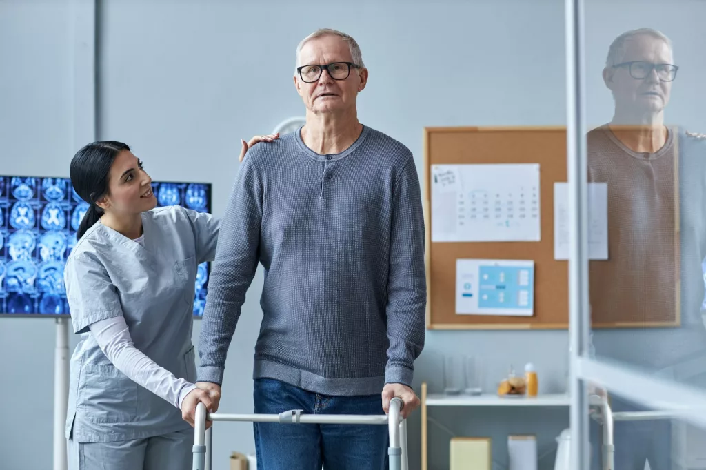 Smiling nurse assisting senior man using mobility walker