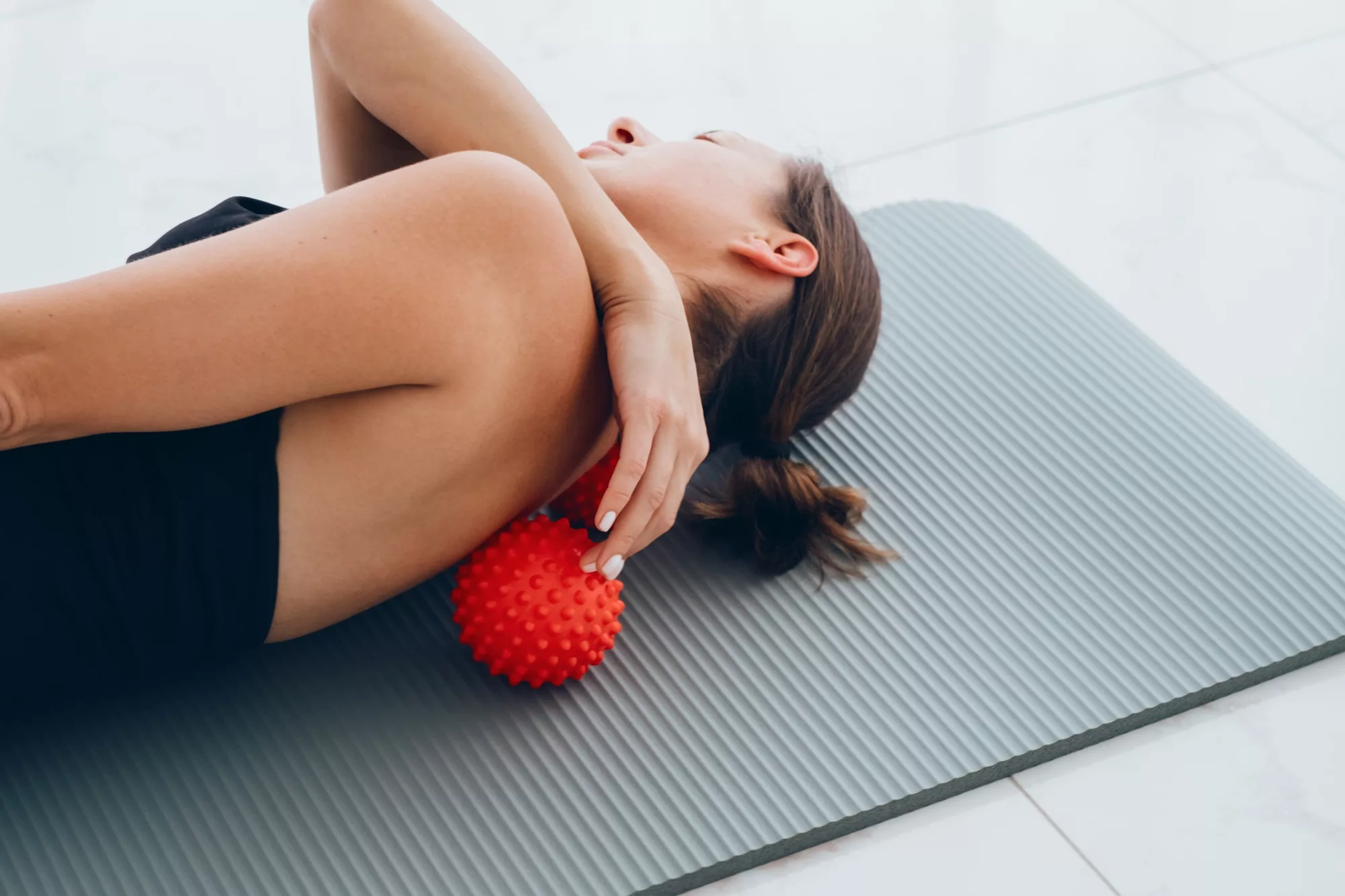 Woman lying on small balls to eliminate back pain, massage stiff muscles.