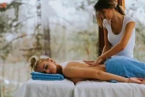 Beautiful young woman lying and having back massage in spa salon during winter season