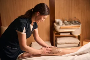 Experienced masseuse giving detox massage to female client