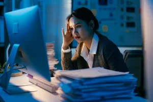 Young business professional dealing with a large amount of paperwork and looking stressed while work