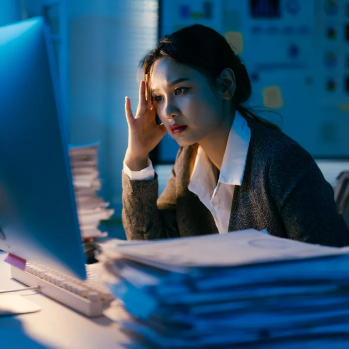 Young business professional dealing with a large amount of paperwork and looking stressed while work