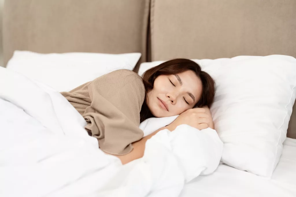 Young Woman Sleeping Peacefully On White Hotel Bed