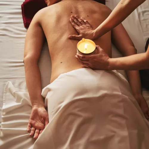 Hand of massage therapist spreading wax on female spine