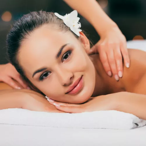 woman relaxing and having massage at spa salon and looking at camera